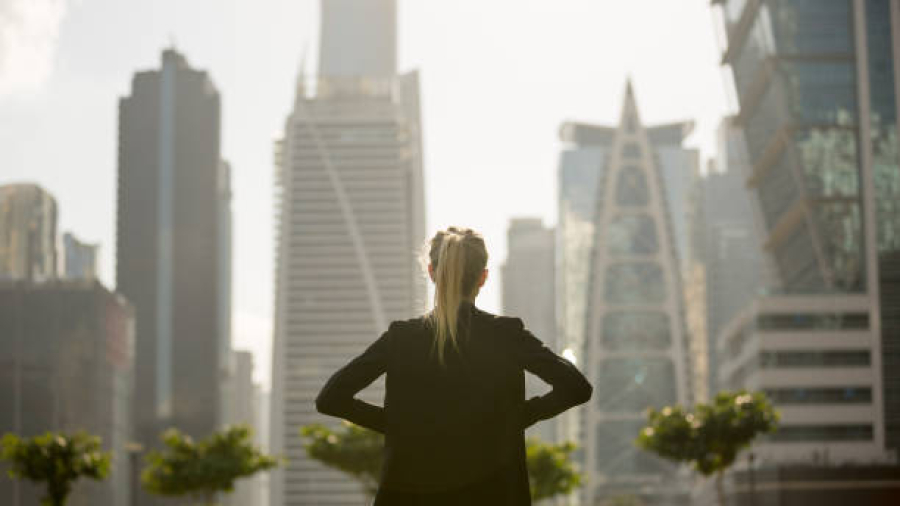 Confident business woman standing strong looking at the city high-rises view. Business ambition and aspiration.